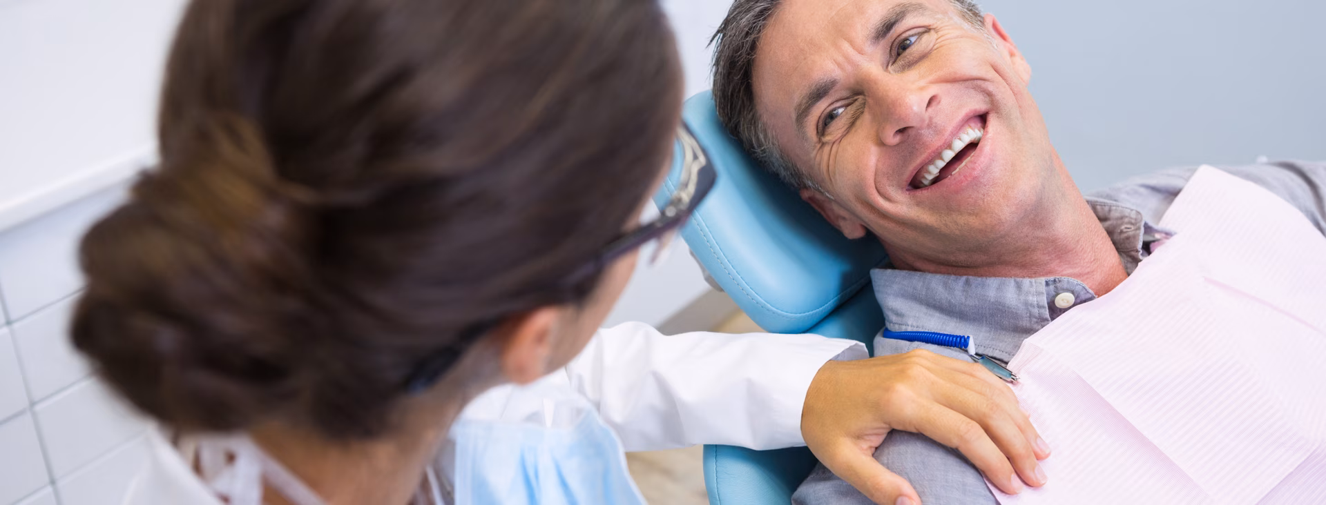 Smiling patient in the dental chair talking with the dentist